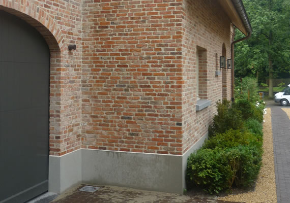 De woning is rondom afgewerkt met een cementplint dewelke als afwerking egaal gekrast is.
